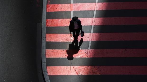 A city worker walks between shadows cast by office properties in the La Defense business district in Paris, France, on Wednesday, June 9, 2021. Talks with labor unions are underway for a broad framework agreement on working from home, l’Obs reported, citing an interview with Labor Minister Elisabeth Borne. Photographer: Nathan Laine/Bloomberg