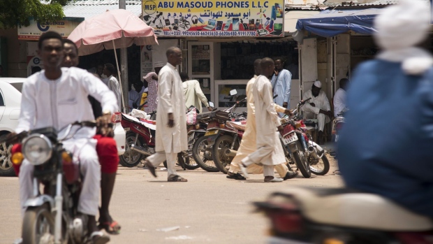 Pedestrians pass a mobile phone store in N'Djamena, Chad, on Wednesday, Aug. 16, 2017. African Development Bank and nations signed agreement to finance a project linking the town of Ngouandere in Cameroon and Chad’s capital, N’Djamena, according to statement handed to reporters in Cameroonian capital, Yaounde in July. Photographer: Xaume Olleros/Bloomberg