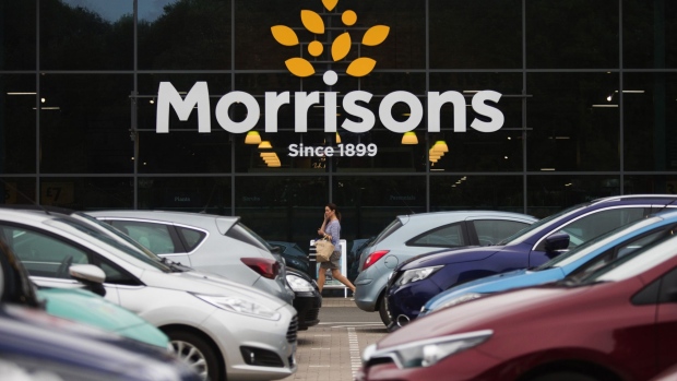 A customer passes parked cars in the parking lot outside a Morrisons supermarket, operated by Wm Morrison Supermarkets Plc, in Saint Ives, U.K., on Wednesday, Aug. 19, 2020. Morrison shares rose after the U.K. grocer and Amazon.com Inc. said customers can now do their full Morrisons food shop on Amazon.co.uk.