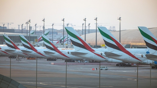 Passenger aircraft, operated by Emirates, stand beside the terminal building at Dubai International Airport in Dubai, United Arab Emirates, on Monday, May 18, 2020. Emirates Group is considering plans to cut about 30,000 jobs as the operator of the world’s largest long-haul carrier seeks to reduce costs after the coronavirus pandemic grounded air travel. Photographer: Christopher Pike/Bloomberg