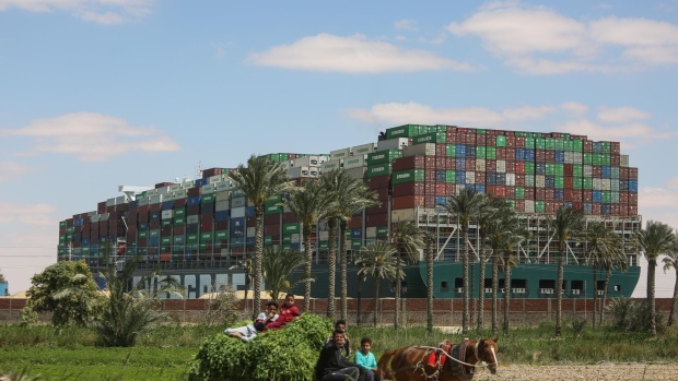 Farmers on a horse-drawn cart passes The 'Ever Given' container ship blocking transit along the Suez Canal in Ismailia, Egypt, on Sunday, March 28, 2021. A new attempt could be made Sunday to re-float the 400-meter-long container ship blocking the�Suez�Canal.