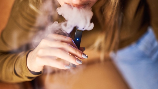 A person smokes a Juul Labs Inc. e-cigarette.