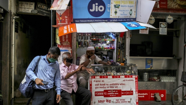 A pedestrian wearing a protective mask walks past advertisements for Jio Platforms Ltd., the mobile network of Reliance Industries Ltd., and Bharti Airtel Ltd. displayed at a store in Mumbai, India, on Tuesday, July 14, 2020. Google is in advanced talks to buy a $4 billion stake in Jio, the digital arm of Indian billionaire Mukesh Ambani's conglomerate, people familiar with the matter said, seeking to join rival Facebook Inc. in chasing growth in a promising internet and e-commerce market.