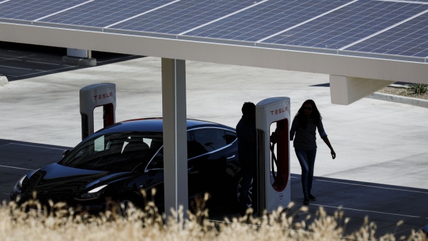 Customers unplug a Tesla Inc. Model 3 electric vehicle charging beneath a solar panel canopy at the Tesla Supercharger station in Kettleman City, California, U.S., on Wednesday, July 31, 2019. Electric vehicles have been adopted rapidly in California, compared to the rest of the U.S., accounting for about 44% of total sales in 2018. Photographer: Patrick T. Fallon/Bloomberg