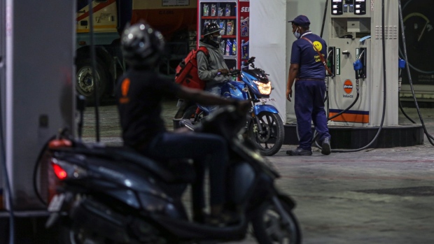 An attendant assists a motorcyclist refueling at an Indian Oil Corp. gas station in Bengaluru, India.
