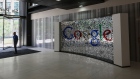 A visitor passes a sign featuring Google Inc.'s logo inside their U.K. headquarters at Six St Pancras Square in London. Photographer: Chris Ratcliffe/Bloomberg