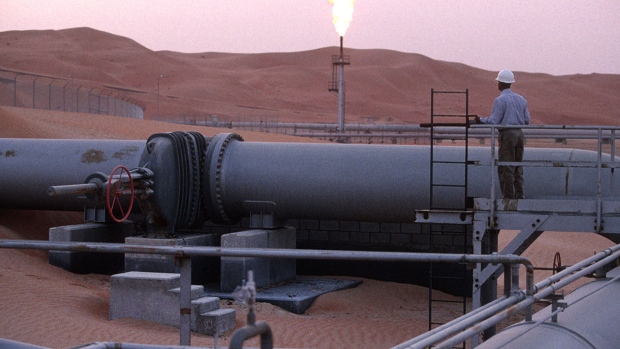 A worker stands at a pipeline, watching a flare stack at the Saudi Aramco oil field complex facilities at Shaybah, in Saudi Arabia. Saudi Aramco, as it’s known, is in talks with international and local banks to replace an undrawn $4 billion loan, the people said, asking not to be identified as negotiations are private.