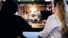 A bartender wearing a protective mask pours drinks while customers sit at the bar at the Chelsea Bell restaurant in New York, U.S., on Monday, May 3, 2021. New York City is moving to fully reopen by July 1 with arenas, gyms, stores, restaurants and hair salons returning, Mayor Bill de Blasio said. Photographer: Nina Westervelt/Bloomberg