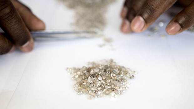 An employee grades a pile of rough diamonds at the Namibian Diamond Trading Co. (NTDC) diamond processing and valuation center, a joint venture between De Beers Group and Namdeb Diamond Corp. operated by Anglo American Plc, in Windhoek, Namibia, on Wednesday, June 14, 2017. The world's biggest diamond producer has spent $157 million on a state-of-the-art exploration vessel that will scour 6,000 square kilometers (2,300 square miles) of ocean floor for gems, an area about 65 percent bigger than Long Island. Photographer: Simon Dawson/Bloomberg