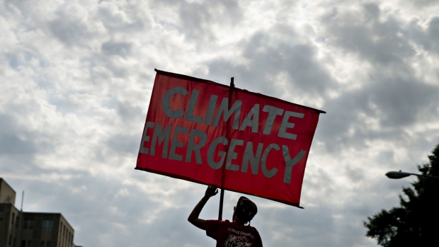 A protester holds a sign that reads "Climate Emergency" while blocking an intersection during the Shut Down DC climate demonstration in Washington, D.C., U.S., on Monday, Sept. 23, 2019. Heads of state from France to India are gathering in New York this week along with some of the world's top corporate leaders for a climate summit as protests demanding curbs in carbon emissions expand across the globe. Photographer: Andrew Harrer/Bloomberg
