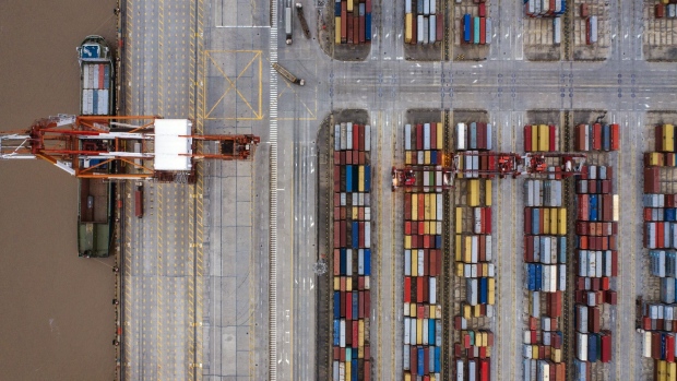 A container ship is docked next to a gantry crane as shipping containers sit stacked at the Yangshan Deepwater Port, operated by Shanghai International Port Group Co. (SIPG), in this aerial photograph taken in Shanghai, China, on Friday, May 10, 2019. The U.S. hiked tariffs on more than $200 billion in goods from China on Friday in the most dramatic step yet of President Donald Trump's push to extract trade concessions, deepening a conflict that has roiled financial markets and cast a shadow over the global economy. Photographer: Qilai Shen/Bloomberg