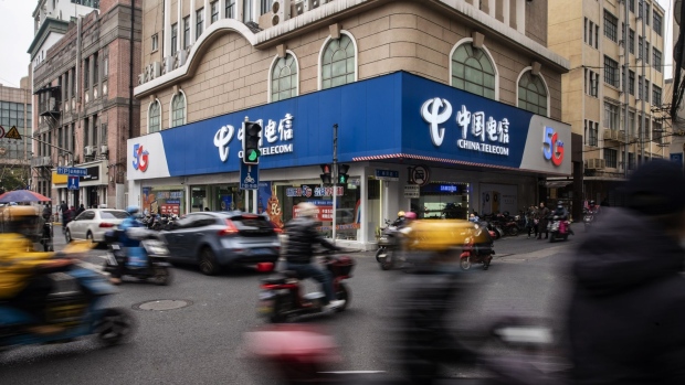 Vehicles travel past a China Telecom Corp. store in Shanghai, China, on Wednesday, Jan. 6, 2021. The New York Stock Exchange is considering reversing course a second time to delist three major Chinese telecommunications firms after conferring further with senior authorities on how to interpret an executive order President Donald Trump issued Nov. 12, according to people familiar with the matter. Photographer: Qilai Shen/Bloomberg