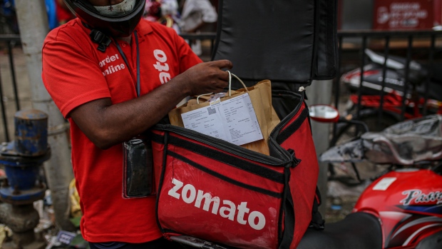 Delivery riders for Zomato Ltd., center, and Swiggy, operated by Bundl Technologies Pvt., wait to collect orders outside a restaurant in Mumbai, India, on Friday, July 16, 2021. Zomato $1.3 billion initial public offering was fully subscribed on the first day of sale, after anchor funds including BlackRock Inc. bid for 35 times more stock than was offered to them.