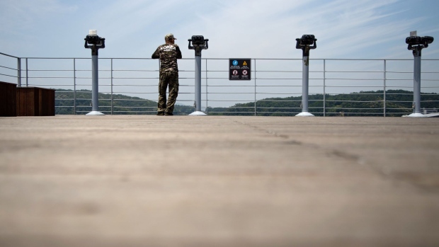 A man wearing a T-shirt with the words "Korea Army" looks across to the North Korean side of the border at the Imjingak pavilion near the Demilitarized Zone (DMZ) in Paju, South Korea, on Wednesday, June 17, 2020. North Korea said it would deploy troops into areas on its side of the border where it had joint projects with South Korea, further escalating tensions with its neighbor a day after destroying a liaison office the two once shared. Photographer: SeongJoon Cho/Bloomberg
