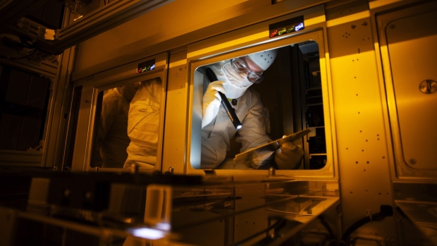 An employee uses a flashlight while performing tool maintenance work on a lithography scanner at Globalfoundries semiconductor fabrication (fab) plant in Dresden, Germany.