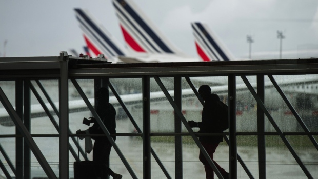 Passengers board a flight near the tail fins of Air France-KLM aircraft at Charles de Gaulle airport in Roissy, France, on Tuesday, May 18, 2021. Airbus SE will buttress its moonshot plan to build a hydrogen aircraft by the middle of the next decade with an effort to power conventional jets with sustainable fuels.
