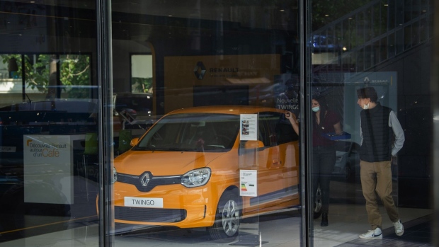 A sales person, left, gestures beside a Renault Twingo E-Tech electric automobile inside a Renault SA showroom in Paris, France, on Wednesday, June 9, 2021. The manufacturer announced on Wednesday the creation of ElectriCity, a wholly owned unit that combines operations at three sites in Douai, Maubeuge and Ruitz and will aim to produce as many as 400,000 vehicles annually.