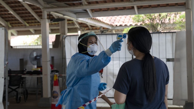 A health worker checks the temperature of a resident at a Covid-19 test site set up at a Housing & Development Board (HDB) public housing estate in the Ang Mo Kio area of Singapore, on Sunday, July 25, 2021. Singapore's government imposed new restrictions last Thursday to curb the spread of a more contagious variant with a surge of cases from clusters related to karaoke lounges and a fishery port. These curbs included banning dining-in and limiting social gatherings to two people. Photographer: Wei Leng Tay/Bloomberg