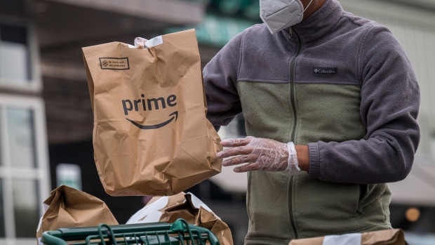 An independent contractor wearing a protective mask and gloves loads Amazon Prime grocery bags into a car outside a Whole Foods Market in Berkeley, California, U.S., on Wednesday, Oct. 7, 2020. With millions of Americans still sheltering in place and cooking their own meals, the grocery industry has been one of the few bright spots in an otherwise battered U.S. economy. Unless, that is, you are Whole Foods Market, the upscale chain acquired three years ago by Amazon.com Inc. Photographer: David Paul Morris/Bloomberg