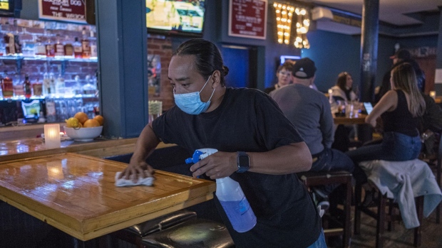 A bartender wearing a protective mask cleans a table inside a bar in San Francisco, California, U.S., on Thursday, May 6, 2021. San Francisco advanced into the least restrictive tier of Californias color-coded reopening system Tuesday, allowing most businesses to expand capacity, bars to start serving indoors and large gatherings to resume inside and outside.