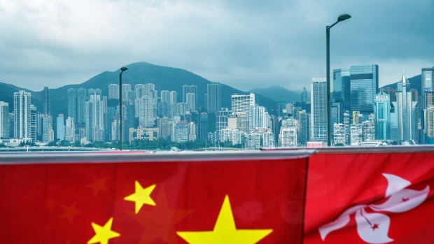 The flags of China, left, and the Hong Kong Special Administrative Region (HKSAR) against the city's skyline ahead of the anniversary of Hong Kong's return to Chinese in Hong Kong, China, on Wednesday, June 30, 2021. The national security law China imposed on Hong Kong a year ago today was much more than a piece of legislation: It showed Beijing was now running the show in the former British colony. Photographer: Lam Yik/Bloomberg