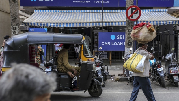 Pedestrians and an auto-rickshaw pass a State Bank of India Ltd. (SBI) branch in Mumbai, India, on Friday, March 6, 2020. SBI has been selected to lead a consortium that will inject new capital into Yes Bank Ltd., people familiar with the matter said, after the Indian government stepped in to organize a rescue plan. Photographer: Dhiraj Singh/Bloomberg