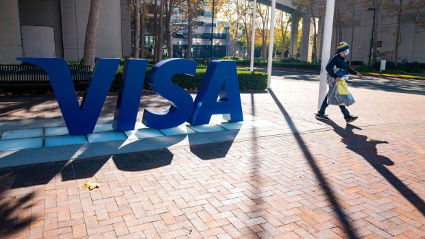 A pedestrian wearing a protective mask walks past Visa Inc. headquarters in Foster City, California, U.S., on Monday, Nov. 23, 2020. Visa Inc.is delaying plans to raise the swipe fees paid by certain U.S. merchants each time a customer uses a credit card in-store as the coronavirus pandemic continues to crimp commerce across the country. Photographer: David Paul Morris/Bloomberg