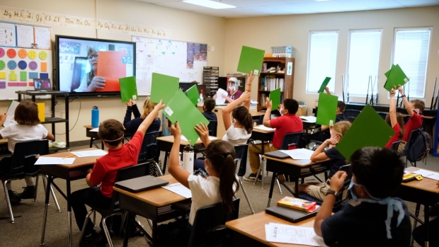 Students wearing protective masks raise their hands in a classroom as a teacher gives a lesson remotely at a public charter school in Provo, Utah, U.S., on Thursday, Aug. 20, 2020. Students and staff in Utah who don’t wear a mask in K-12 schools in accordance with the Governor Gary Herbert’s mandate can be charged with a misdemeanor, reported the Salt Lake Tribune. George Frey/Bloomberg Photographer: George Frey/Bloomberg