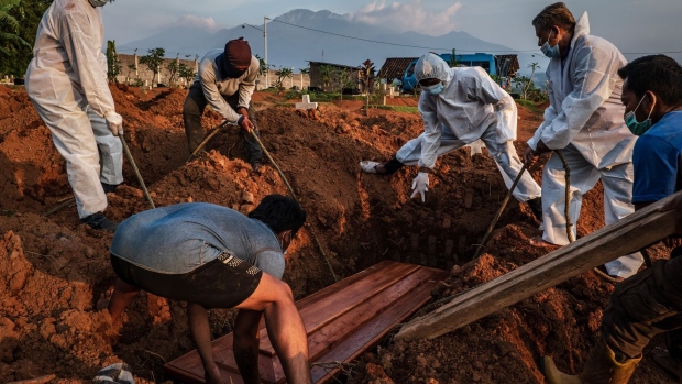 SEMARANG, CENTRAL JAVA, INDONESIA - JULY 02: Grave diggers conduct a burial at Jatisari public cemetery, reserved for suspected COVID-19 victims on July 2, 2021 in Semarang, Central Java, Indonesia. Indonesia's President Joko Widodo announced on Thursday to place 'emergency restrictions' on Java and Bali islands from July 3 to 21, aiming to tame the recent COVID-19 surge. The country recorded more than 25,000 new infections and the 539 people reported dead on Friday. (Photo by Ulet Ifansasti/Getty Images)