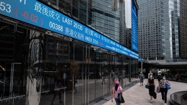 Pedestrians wearing protective masks walk past an electronic ticker displaying the share price of Hong Kong Exchanges & Clearing Ltd. (HKEX) at the Exchange Square complex in Hong Kong, China, on Wednesday, Aug. 19, 2020. HKEX posted a 1% gain in profit, benefiting from a spate of high-profile Chinese stock listings and a pick up in trading as the pandemic and political tensions stoked volatility. Photographer: Roy Liu/Bloomberg