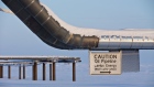A caution sign hangs from an oil pipeline on the North Slope in Harrison Bay, Alaska.