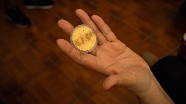 A person holds a Bitcoin token at the Bitcoin automated teller machine (ATM) in El Zonte, El Salvador, on Monday, June 14, 2021. El Salvador has become the first country to formally adopt Bitcoin as legal tender after President Nayib Bukele said congress approved his landmark proposal. Photographer: Cristina Baussan/Bloomberg