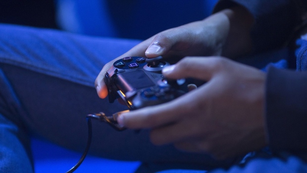 A gamer uses a Sony Corp. Playstation 4 controller to play a video game at EGX 2015 video gaming conference in Birmingham, U.K., on Thursday, Sept. 24, 2015. Virtual reality has been a focus of both Hollywood and Silicon Valley as entertainment and technology companies look for new ways to excite audiences. Photographer: Bloomberg/Bloomberg