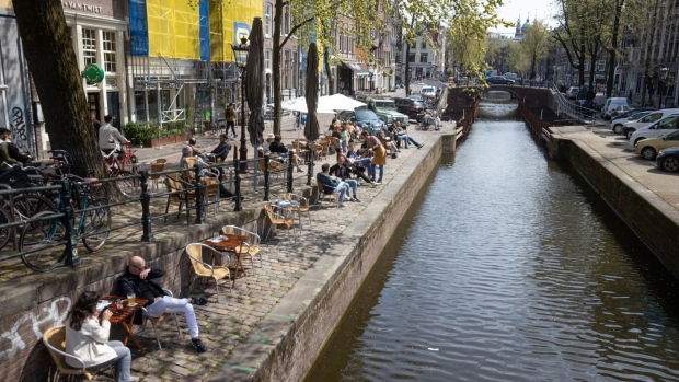Customers use the canal side seating of restaurants in Amsterdam, Netherlands, on Wednesday, April 28, 2021. Shops and outdoor seating at restaurants and cafes have partially reopened as more people are getting vaccinated. Photographer: Peter Boer/Bloomberg
