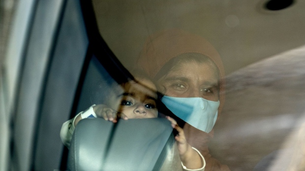 A refugee from Afghanistan holds a baby on a bus after arriving at Washington Dulles International Airport in Dulles, Virginia, U.S., on Tuesday, Aug. 31, 2021. The departure of the last U.S. military plane from Afghanistan left the region facing uncertainty, with the Taliban seeking to cement control of a nation shattered by two decades of war and an economy long dependent on foreign aid and opium sales. Photographer: Stefani Reynolds/Bloomberg