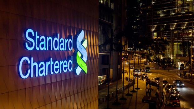 Signage is illuminated atop a Standard Chartered Plc bank branch at night in Hong Kong, China, on Thursday, July 25, 2019. Standard Chartered is scheduled to release interim earnings results on Aug. 1. Photographer: Paul Yeung/Bloomberg