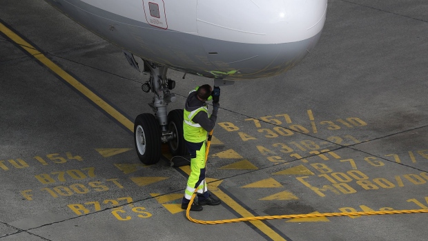 A ground crew member connects a fuel hose to an Airbus A321 aircraft Photographer: Kristian Bocsi/Bloomberg