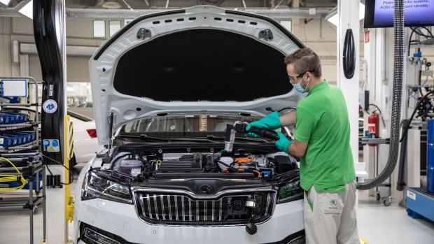 An employee wears a protective face mask while securing a combustion engine fitting on a Skoda Superb hydrid automobile on the assembly line at the Skoda Auto AS factory, operated by Volkswagen AG, in Kvasiny, Czech Republic, on Tuesday, June 9, 2020. Across the 12-brand group, Volkswagen plans to invest 33 billion euros ($37.5 billion) by 2024 in a push to become the world’s largest electric-car maker, including 11 billion euros alone for the VW brand. Photographer: Milan Jaros/Bloomberg