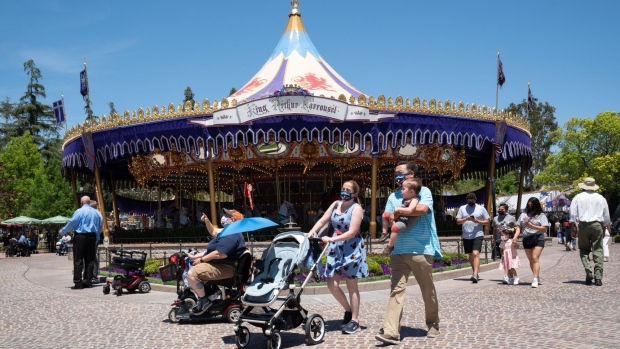 Guests wearing protective masks walk past the King Arthur Carrousel attraction during the reopening of the Disneyland theme park in Anaheim, California, U.S., on Friday, April 30, 2021. Walt Disney Co.’s original Disneyland resort in California is sold out for weekends through May, an indication of pent-up demand for leisure activities as the pandemic eases in the nation’s most-populous state. Photographer: Bing Guan/Bloomberg