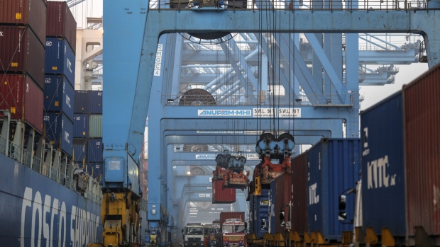 Gantry cranes load shipping containers onto trucks from the Cosco New York container ship docked at the Jawaharlal Nehru Port, operated by Jawaharlal Nehru Port Trust (JNPT), in Navi Mumbai, Maharashtra, India, on Saturday, Dec. 16, 2017. Many of the cargo containers passing through India's busiest port in Mumbai have a small piece of Japan Inc. attached: Devices from NEC Corp. that can be tracked as the containers rumble through the interior of Asia's third-largest economy. Photographer: Dhiraj Singh/Bloomberg