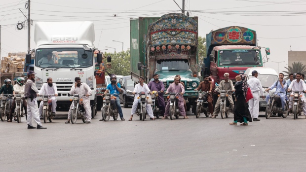 A pedestrian crosses a street as motorists wait at an intersection on Karachi Port Road in Karachi, Pakistan, on Monday, July 9, 2018. The Pakistan economy is in distress. How else to describe an emerging market that has seen three currency devaluations since December, depleted its foreign-currency reserves and may soon ask for a bailout from the International Monetary Fund, less than two years after its last $6.6 billion emergency cash infusion.