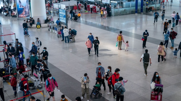 Travelers walk through Beijing Capital International Airport in Beijing, China, on Saturday, May 1, 2021. Tickets for everything from domestic flights to theme parks are rapidly selling out in China ahead of its Labor Day holiday as the nation’s recovery gathers pace.