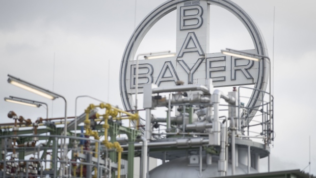 A Bayer AG logo sits above pipework at the Bayer CropScience AG crop protection production site in Dormagen, Germany, on Wednesday, March 21, 2018. Bayer cleared one big hurdle for its $66 billion takeover of Monsanto, winning European Union approval for the deal after agreeing to bolster BASF SE by selling it seeds, pesticides and digital agriculture technology.