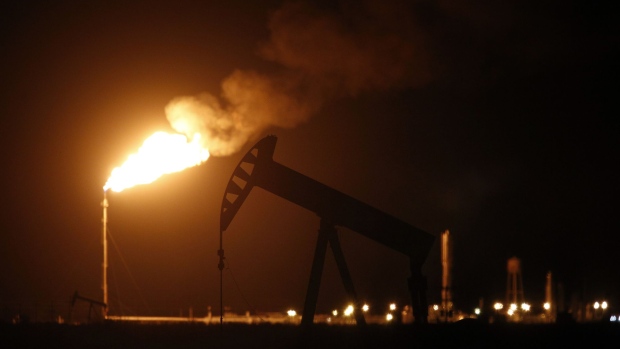 An oil pump jack near a flare at night.