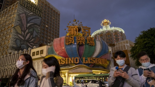 Pedestrians wearing face masks pass the Casino Lisboa, operated by SJM Holdings Ltd., after its lights were switched off at dusk in Macau, China, on Wednesday, Feb. 5, 2020. Casinos in Macau, the Chinese territory that's the world's biggest gambling hub, closed for 15 days as China tries to contain the spread of the deadly coronavirus. Photographer: Justin Chin/Bloomberg