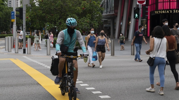 A food delivery courier for Deliveroo Plc cycles at a crossing in Singapore, on Sunday, May 16, 2021. Singapore is returning to the lockdown-like conditions it last imposed a year ago, banning dining-in and limiting gatherings to two people, as a rising number of untraceable virus infections pressures one of the most successful places in the world at Covid containment.