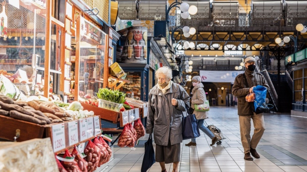 An elderly shopper browses items outside a fresh produce store inside the Grand Market Hall in Budapest, Hungary.