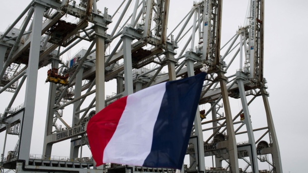 A French national flag flies near ship to shore cranes at the Port of Le Havre in Le Havre, France, on Thursday, Jan. 21, 2021. The market for vessels carrying liquefied natural gas boomed last year as the world’s biggest trading houses and oil majors booked up ships to take advantage of the winter demand boom in fuel demand. Photographer: Nathan Laine/Bloomberg