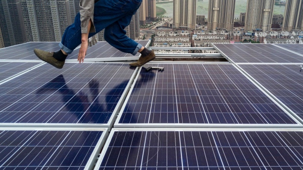 WUHAN, CHINA - MAY 15: A Chinese worker from Wuhan Guangsheng Photovoltaic Company works on a solar panel project on the roof of a 47 story building in a new development on May 15, 2017 in Wuhan, China. China consumes more electricity than any other nation, but it is also the world's biggest producer of solar energy. Capacity in China hit 77 gigawatts in 2016 which helped a 50% jump in solar power growth worldwide. China is now home to two-thirds of the world's solar production, though capacity and consumption remain low relative to its population. Still, the country now buys half of the world's new solar panels which convert sunlight into energy, and are being installed on rooftops in cities and across sprawling fields in rural areas. Greenpeace estimates that by 2030, renewable energy could replace fossil fuels as China's primary source of power, a significant change in a country considered the world's biggest polluter. China's government has officially committed to development of renewable energies to ease the country's dependence on coal and other fossil fuels, though its strategic investments in the solar panel have created intense global competition. (Photo by Kevin Frayer/Getty Images)