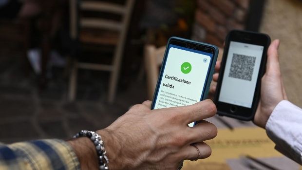 A server scans a digital "green pass" at a restaurant in the Navigli neighborhood of Milan, Italy, on Saturday, Aug. 7, 2021. Italy will restrict many leisure activities for citizens who aren't vaccinated against Covid-19 or haven’t recently tested negative for the virus, amid a surge of delta variant infections. Photographer: Giuliano Berti/Bloomberg